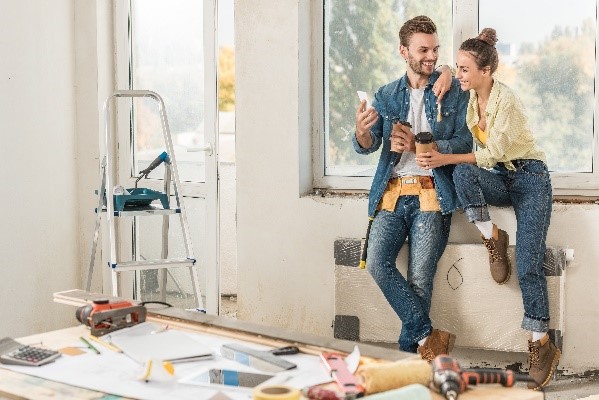Two people looking at a remodeling plan in a room .